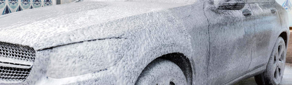 Car Wash from Spray Gun with Foam Aimed at the Car Wheel Stock