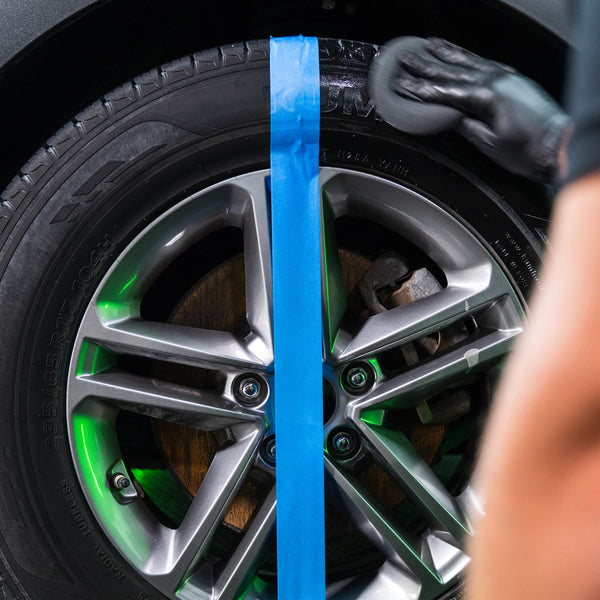 Glossy black tire before & after. Half is prepped using a foam applicator by Turtle Wax with blue tape divider.