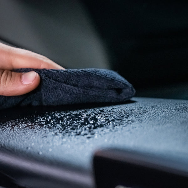 Detailing a car's dashboard: a hand wipes a wet surface with a cloth. Turtle Wax products help refresh automotive interiors.