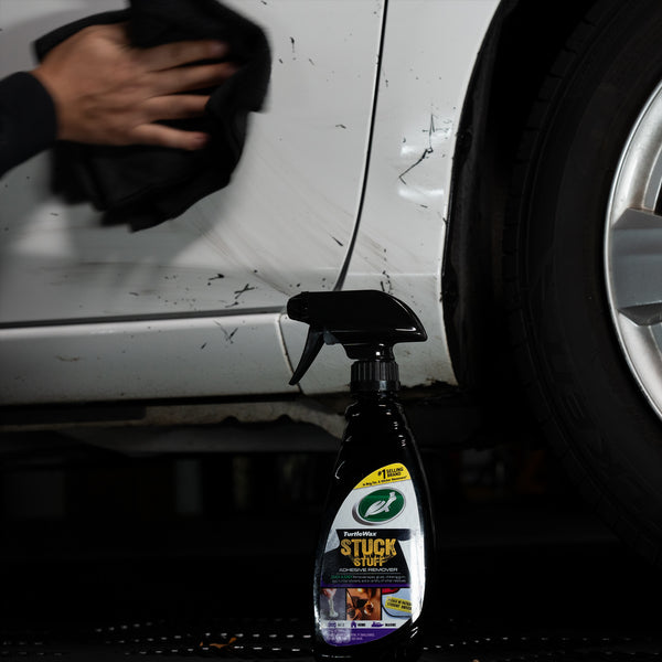 Turtle Wax adhesive remover tackles car sticker residue. Auto detailing shows a hand wiping a white vehicle panel clean.