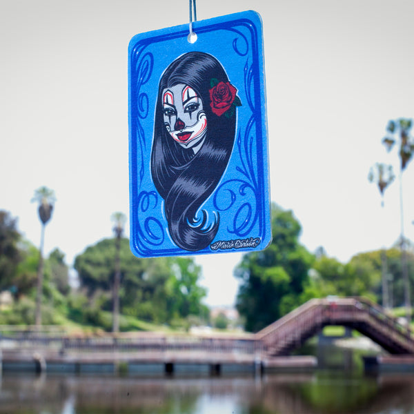 Blue paper car freshener with a clown girl design with a rose in her hair.