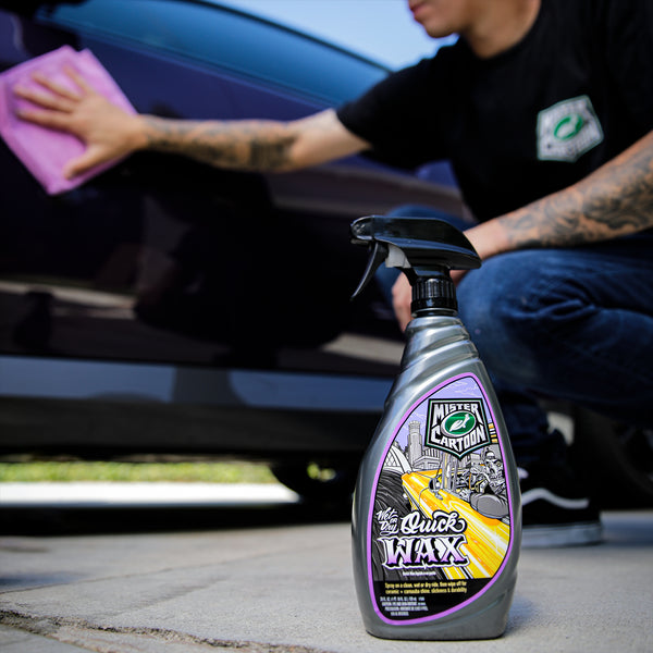 Detailing a car with a Mr. Cartoon Turtle Wax product. Man wiping a vehicle's surface with a cloth; wax bottle in foreground.