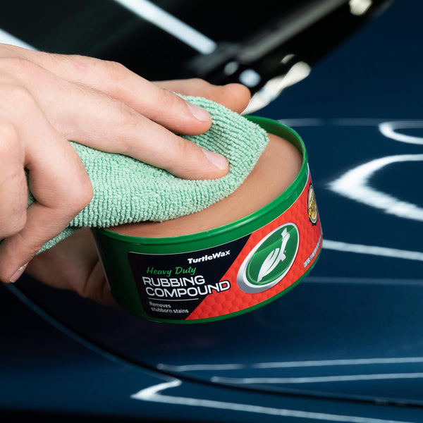 Detailing a blue car finish. Turtle Wax Heavy Duty Rubbing Compound is being applied with a microfiber cloth to remove stubborn stains.