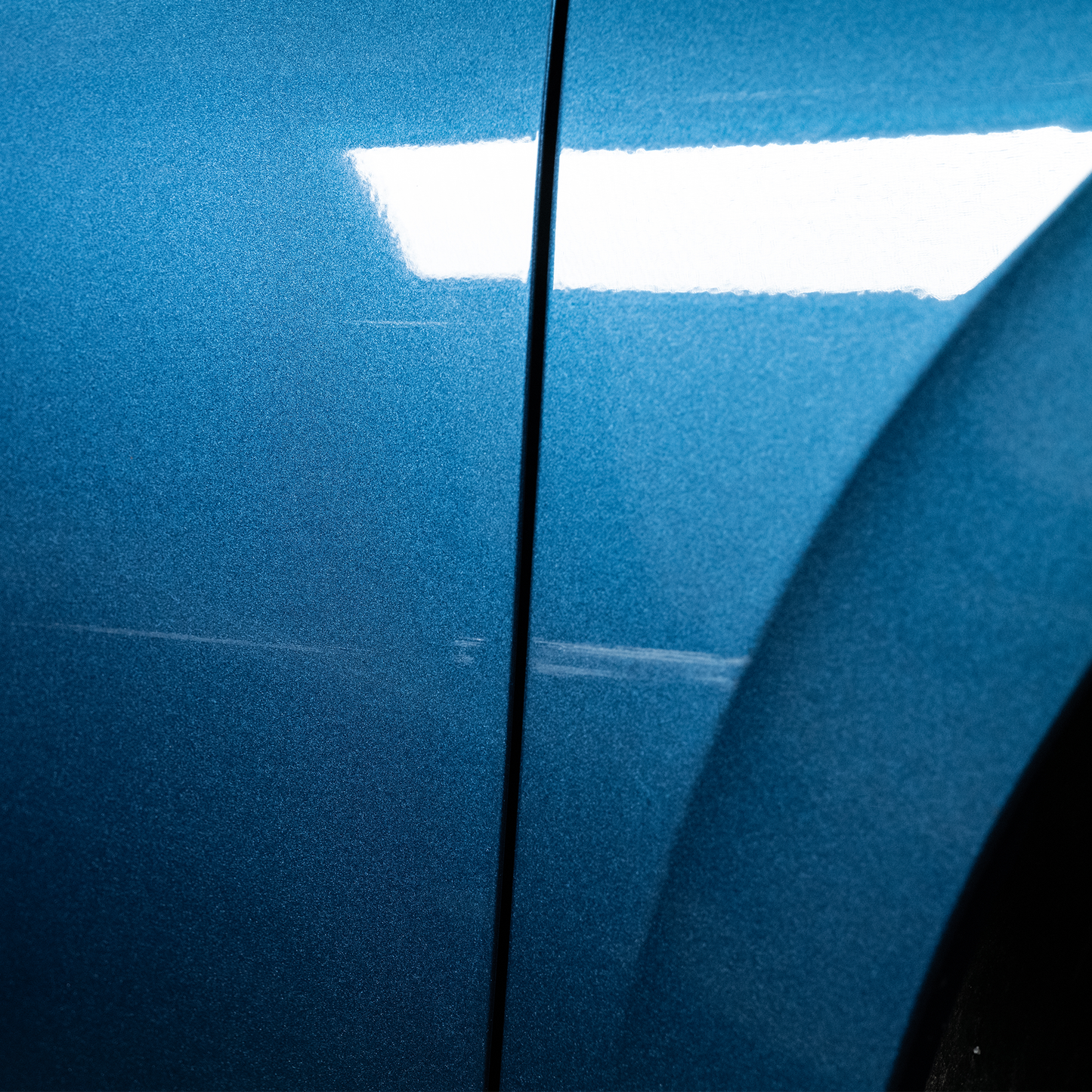 Blue car door with minor scratches. Automotive paint correction needed. Get a Turtle Wax finish.