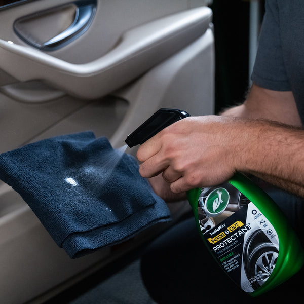 Hand spraying Inside and Out Protectant on a car dashboard to restore shine and protection.