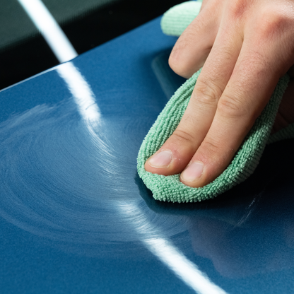 Buffing car paint to a high shine. Hand applies white compound residue with microfiber cloth. Detailing service in US.