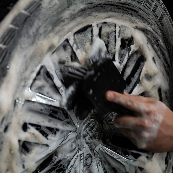 Car enthusiast using Turtle Wax cleaner on tires, hands visible with cleaning mitt.