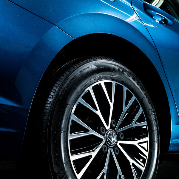 Back tire after Turtle Wax application, mid-rinse with cleaner still foaming.
