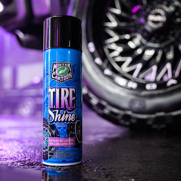 Mr. Cartoon Tire Shine bottle next to a tire with dramatic lighting emphasizing the glossy texture.