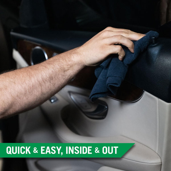 A hand using a black microfiber towel to wipe the black plastic trim on the inside of a cars door frame. 