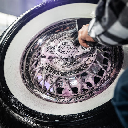 Cleaning classic car wheels. Soap covers rims and whitewall tires during detailing.