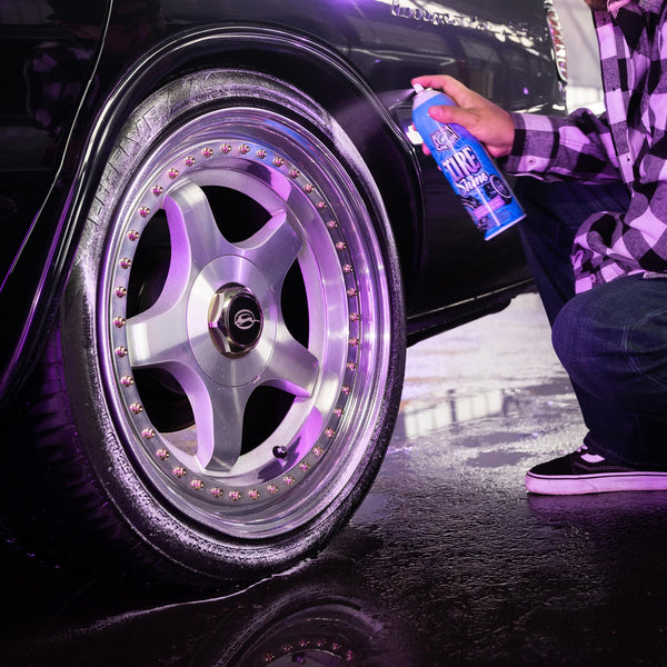 Close-up of gloved hand applying Mr. Cartoon Tire Shine to a tire sidewall using a sponge applicator.