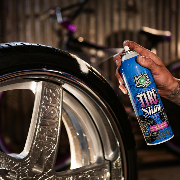 Mr. Cartoon Tire Shine bottle sitting next to a highly polished black tire on a classic car.