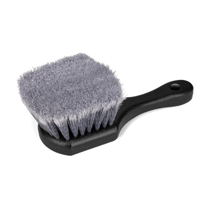 Close-up of a gray, short-handled scrub brush with black handle. Auto detailing tool. Car wash.
