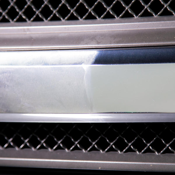 Microfiber cloth buffing a treated surface to a high-gloss finish under garage lighting.