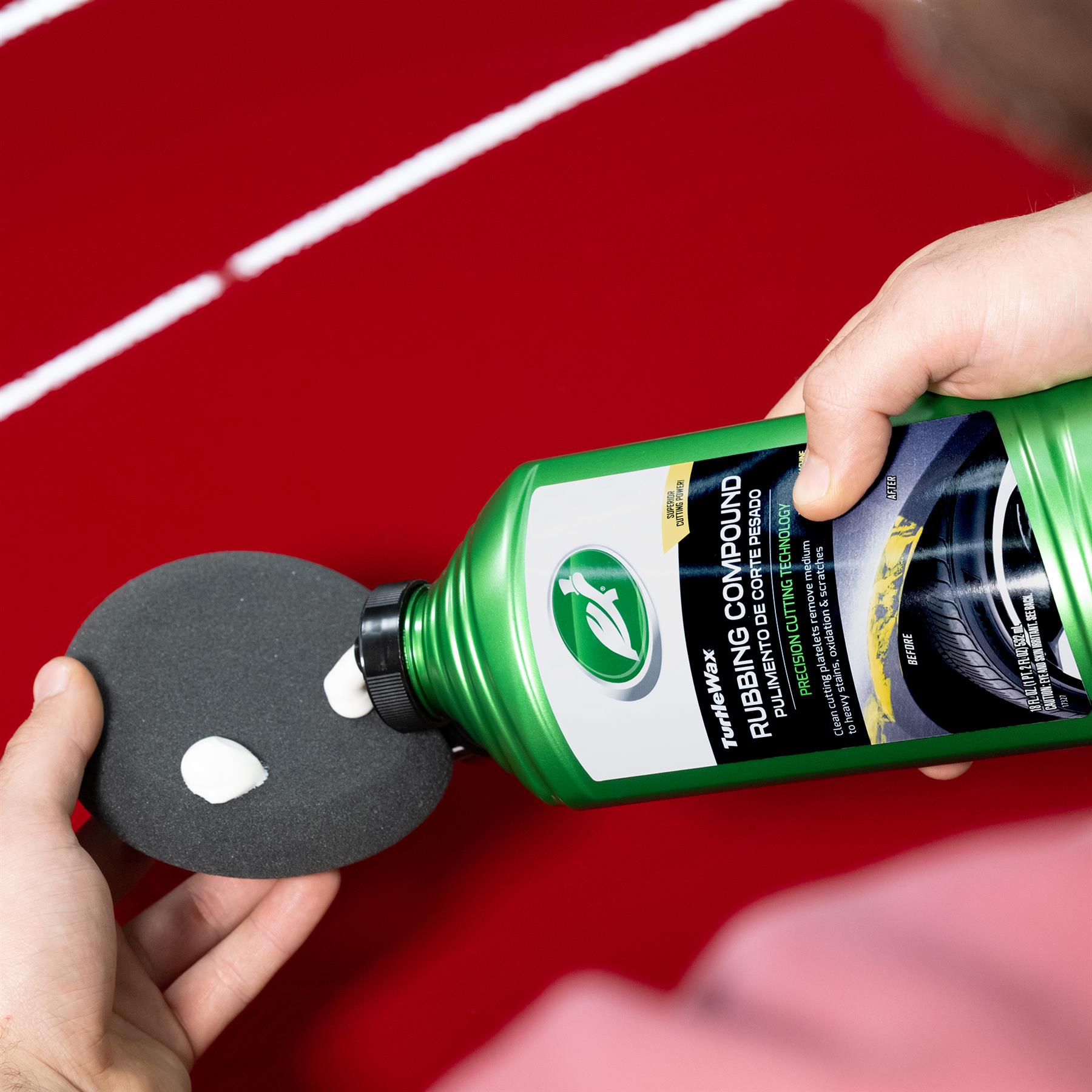 Turtle Wax rubbing compound being applied to a pad for auto body repair on a red car surface.