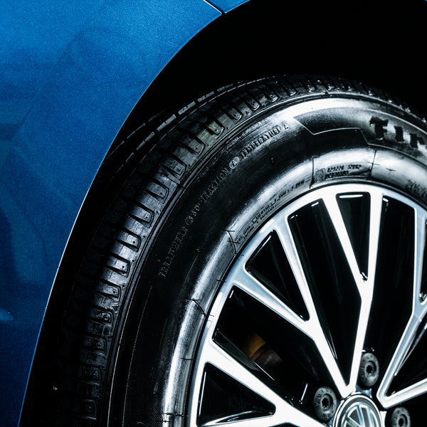A freshly waxed black vehicle in a detailing bay, reflecting bright overhead lights.