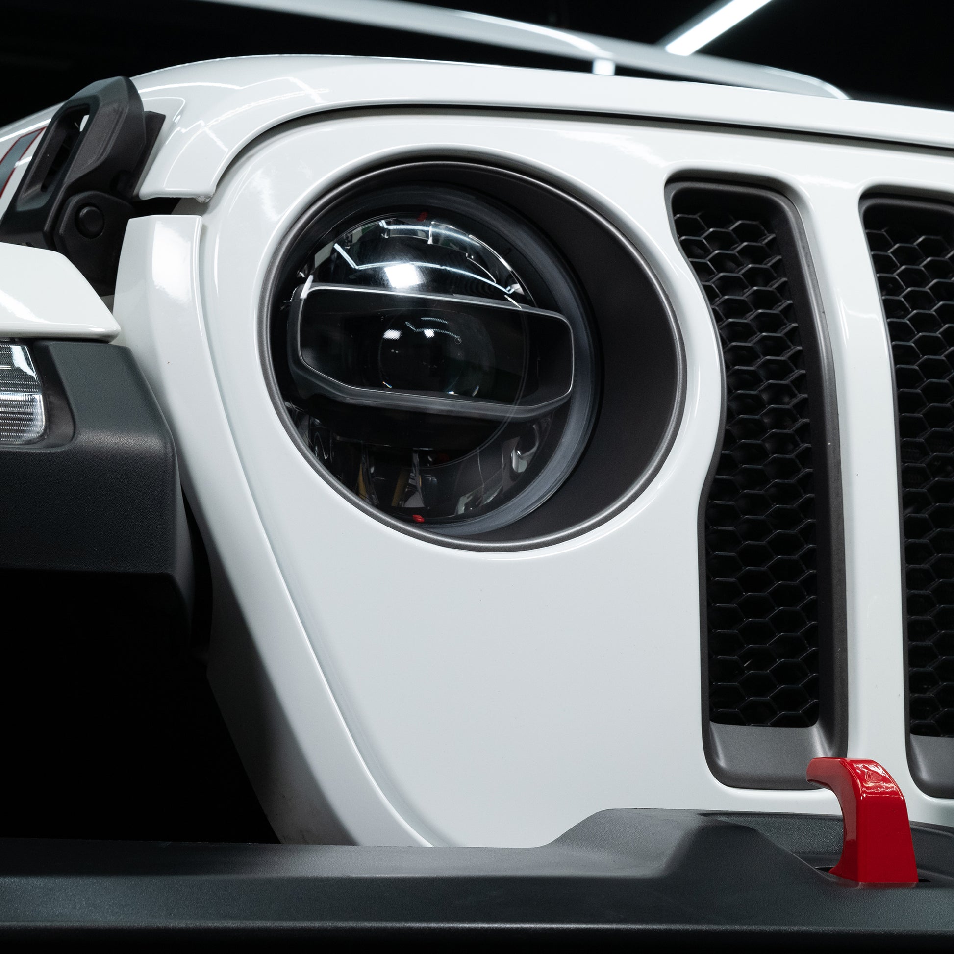 Close-up of a white SUV. The grill and headlight are visible. Car care and detailing may be needed.