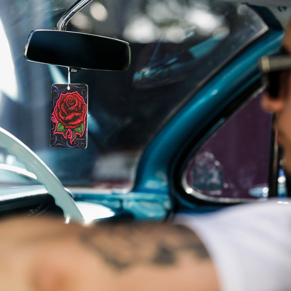 Product display with Mr. Cartoon So Fresh air freshener in focus, laid over a black microfiber towel.