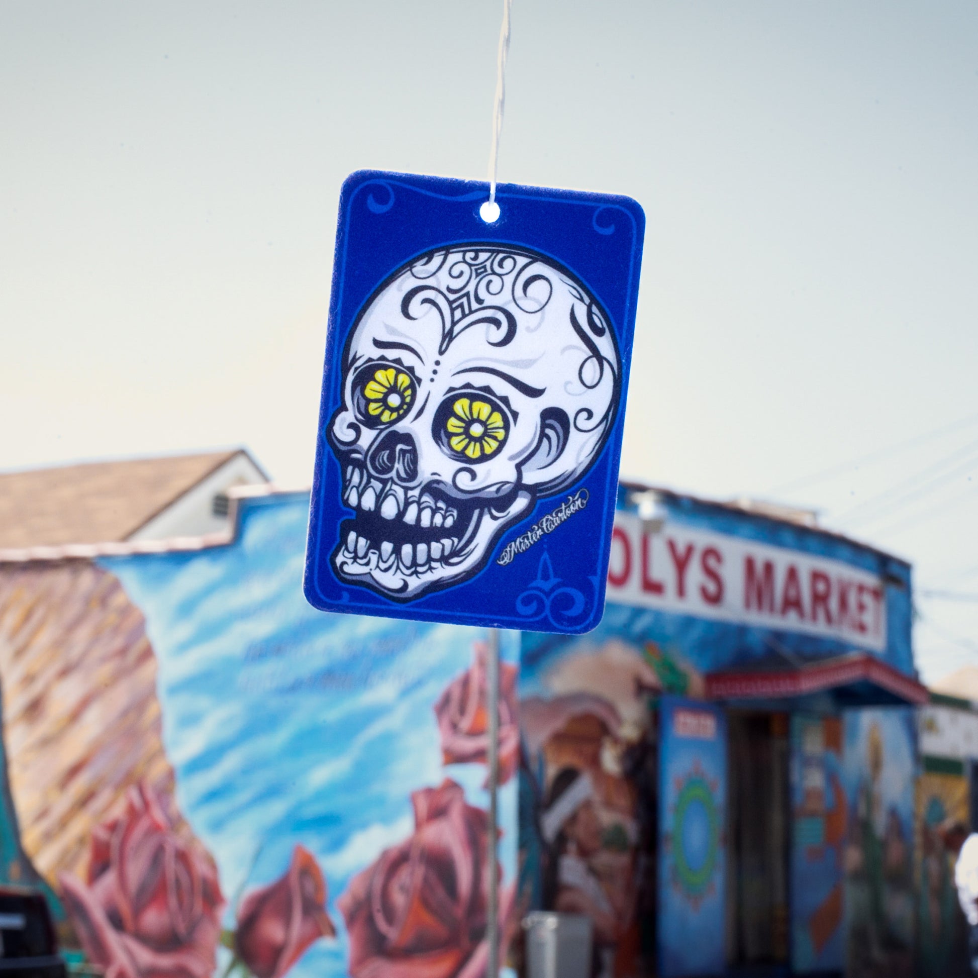 Blue paper freshener with a sugar skull art design hanging by string.