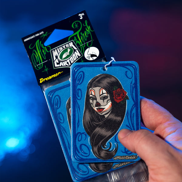 Top-down image of Mr. Cartoon Dreamer air freshener next to accessories like wax and polish tools on a workshop table.