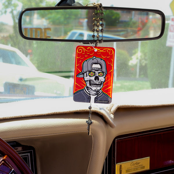 Detailed shot showing the Mr. Cartoon Mr. Low-Lo air freshener held in a hand, emphasizing the custom lowrider artwork and brand details.