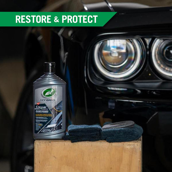 Ceramic Acrylic Black Polish sits on a light wood block against a backdrop of a black sports car. 