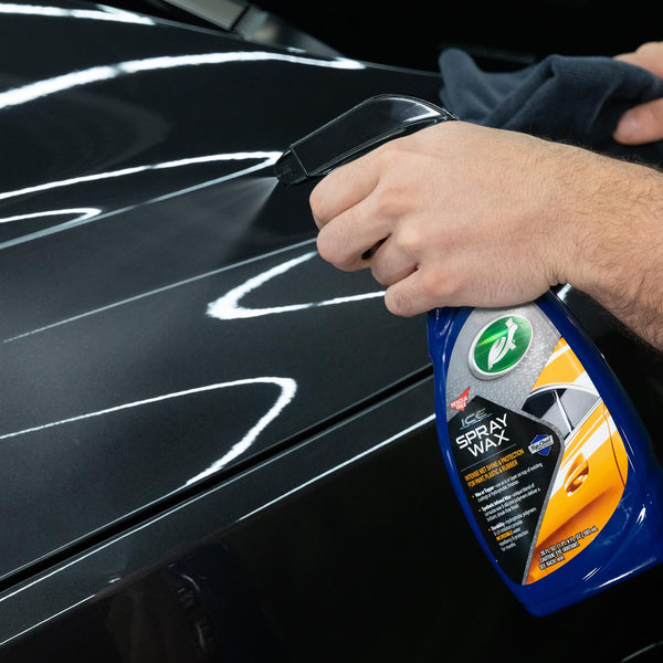 Reflection of overhead lighting on a freshly waxed black hood, showing flawless finish.
