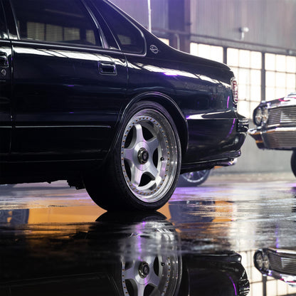 Sleek black Impala on custom wheels reflects in the wet. Classic car detail, automotive lifestyle.
