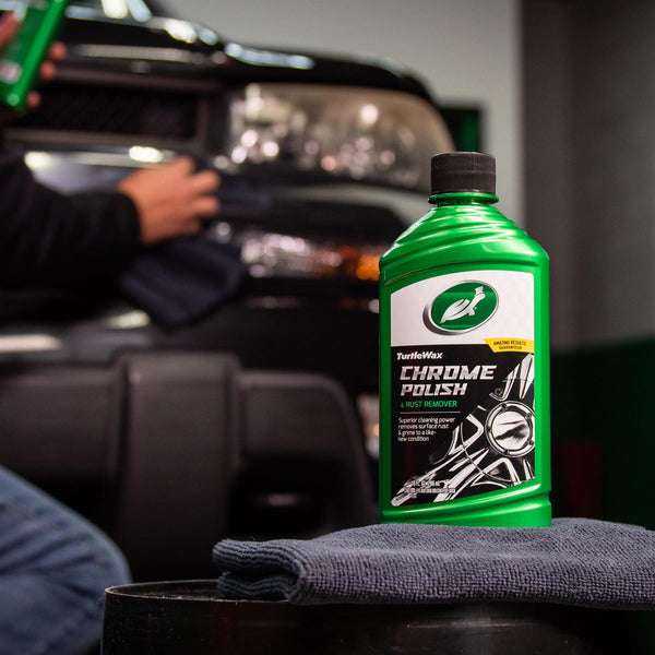 Action shot of detailer applying wax in a circular motion on a car door using a foam pad.