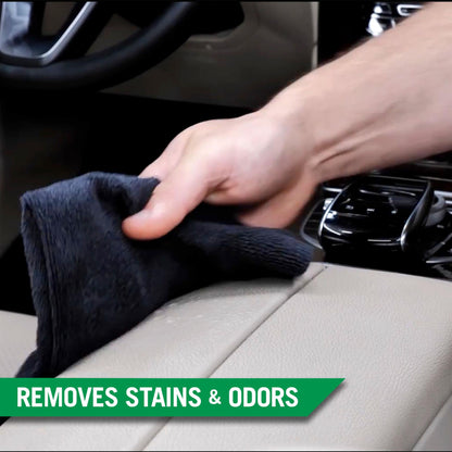 Detailing a car's interior: A hand wipes a beige leather surface with a dark cloth. Car care and cleaning.