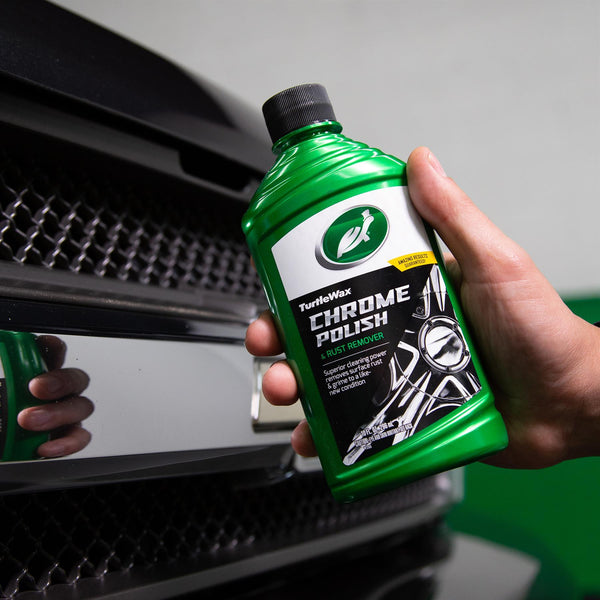 Hand holding Turtle Wax chrome polish. Liquid helps remove rust for a like-new finish on car chrome parts.