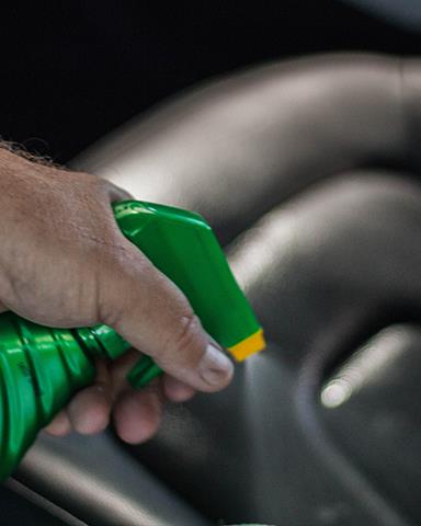 Spraying leather. Green bottle. Hand holding spray bottle. Car interior detailing. Turtle Wax.
