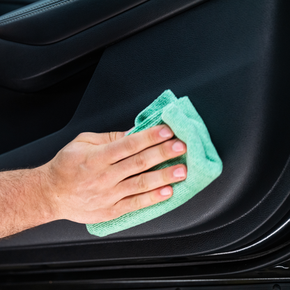 Auto interior cleaning. Hand with microfiber cloth wipes car door panel. Detailing service.