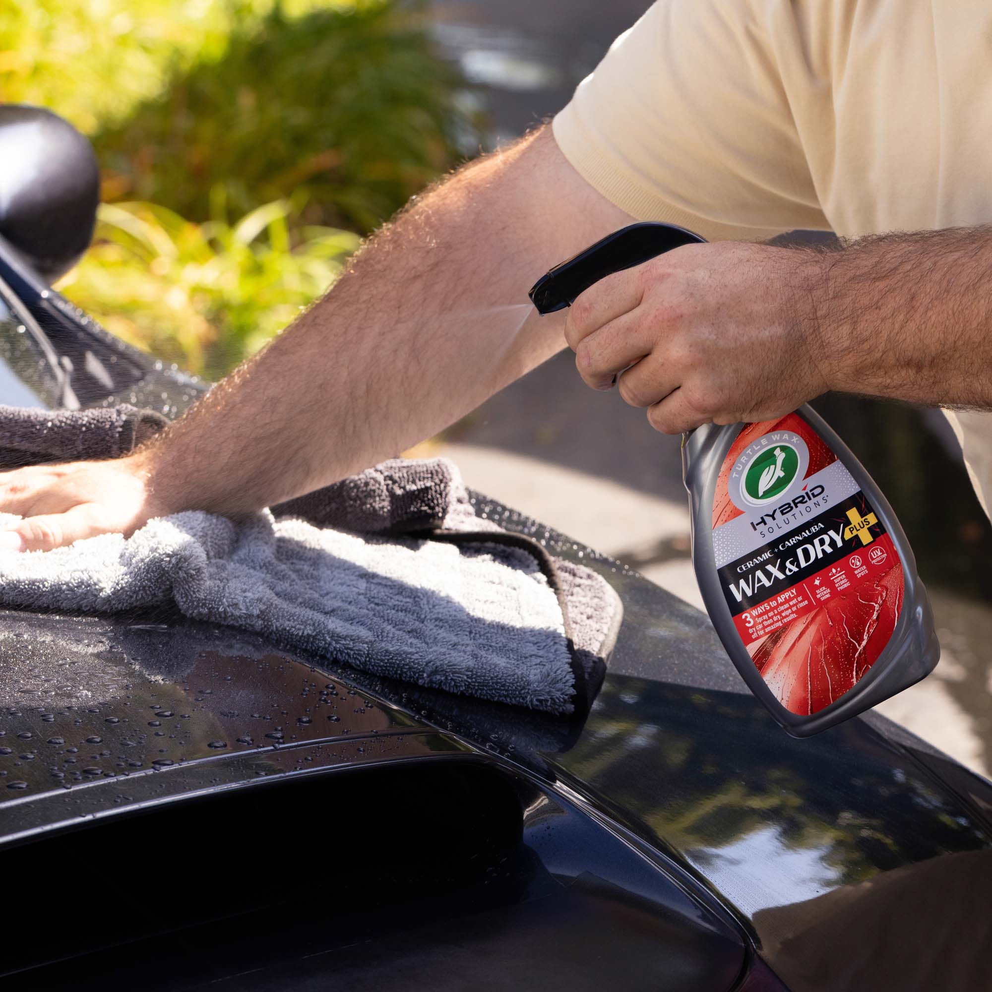 Man using the turtle wax wax and dry plus on a wet surface with a towel