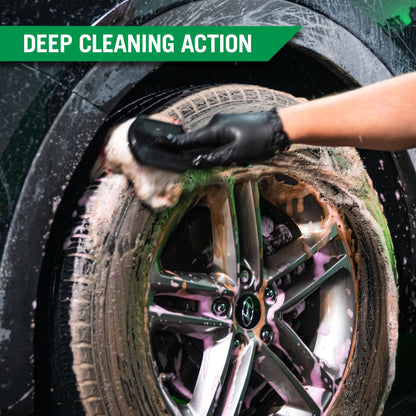 Auto detailer scrubbing a dirty tire with a foamy cleaner. Black gloves and deep cleaning action shown.