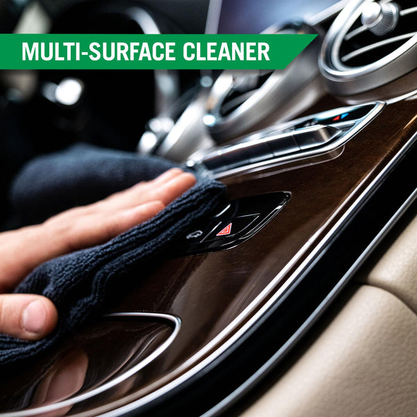 A hand using a black microfiber to clean the controls on a cars dashboard, highlighting the multi-surface cleaning capabilities. 