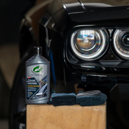 Turtle Wax Hybrid Solutions Ceramic Acrylic Black Polish beside black car with microfiber towels. Car care, detailing.