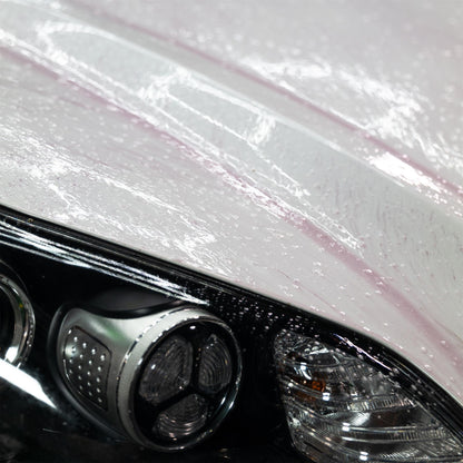 Car detailing. Vehicle cleaning close-up showing water beading on paint and auto headlight.