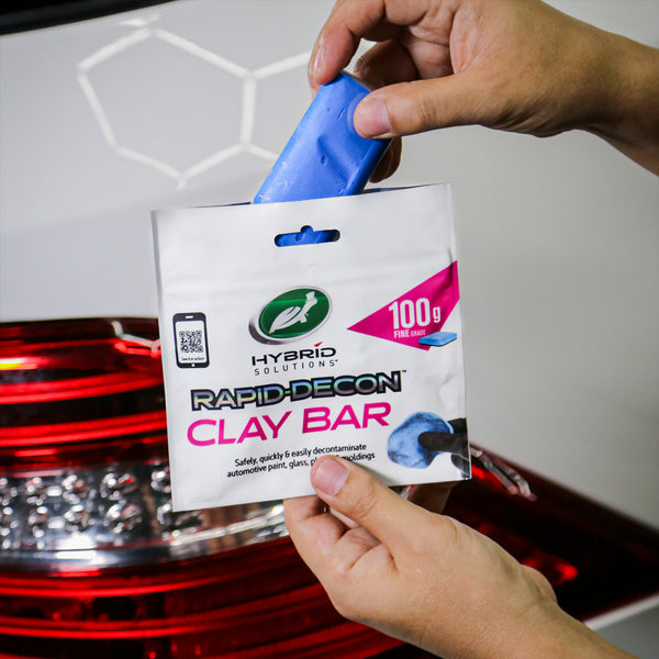Hands wearing gloves applying wax in circular motion, focusing on detail.