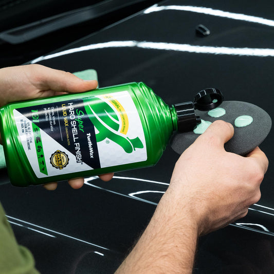 Super Hard shell liquid wax being placed on a rubbing pad ready to use on a black car