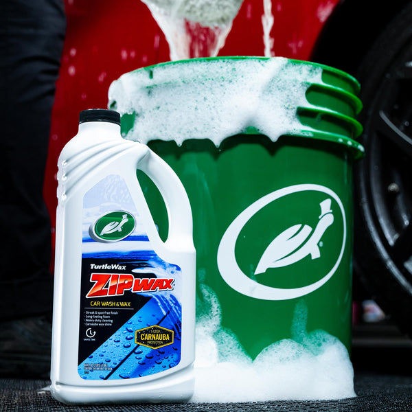 Front-facing product image of Zip Wax Car Wash 64oz bottle, featuring bright yellow label with red branding and water beading graphics.