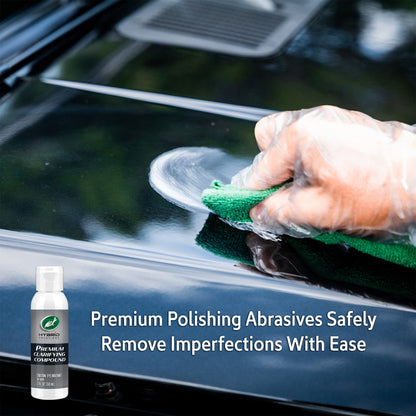 Auto detailing: Hand applies Turtle Wax clarifying compound to a glossy black car surface. Car care and paint correction shown.